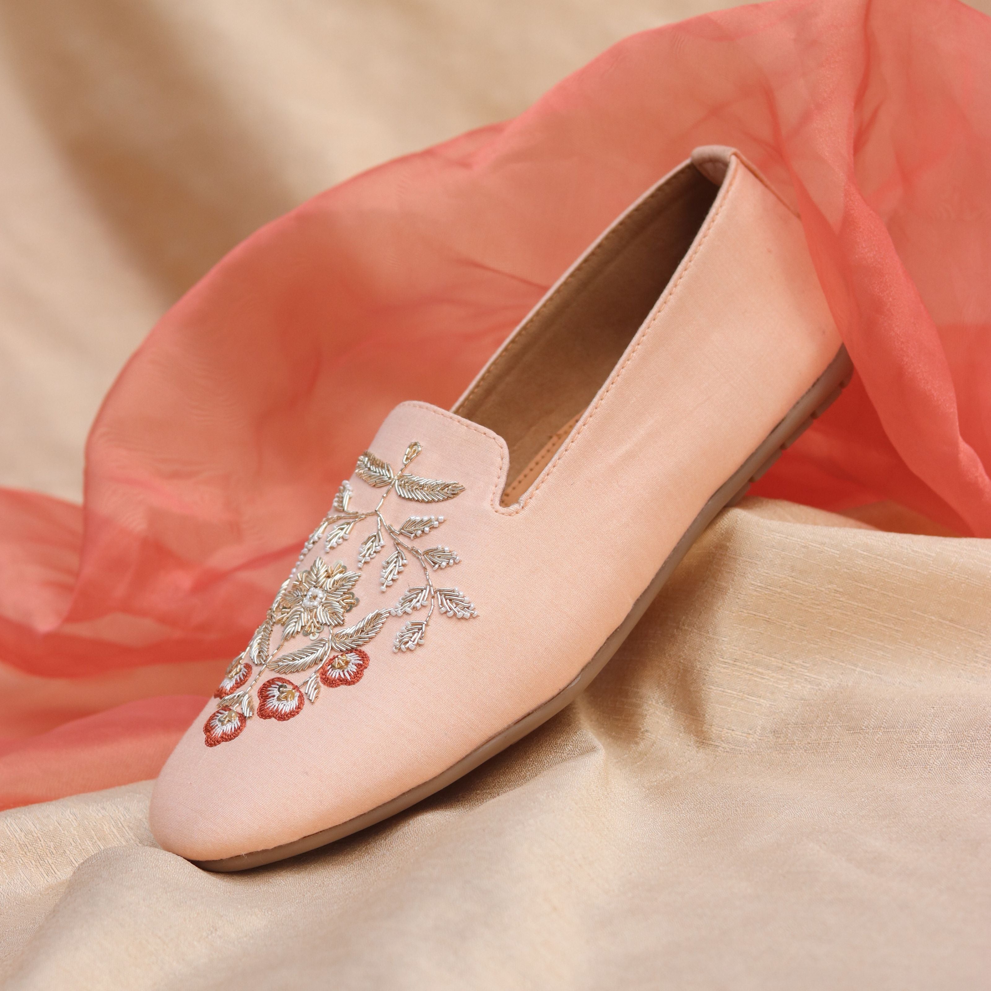 Elegant wedding footwear featuring detailed flower design on soft pink fabric for sangeet.