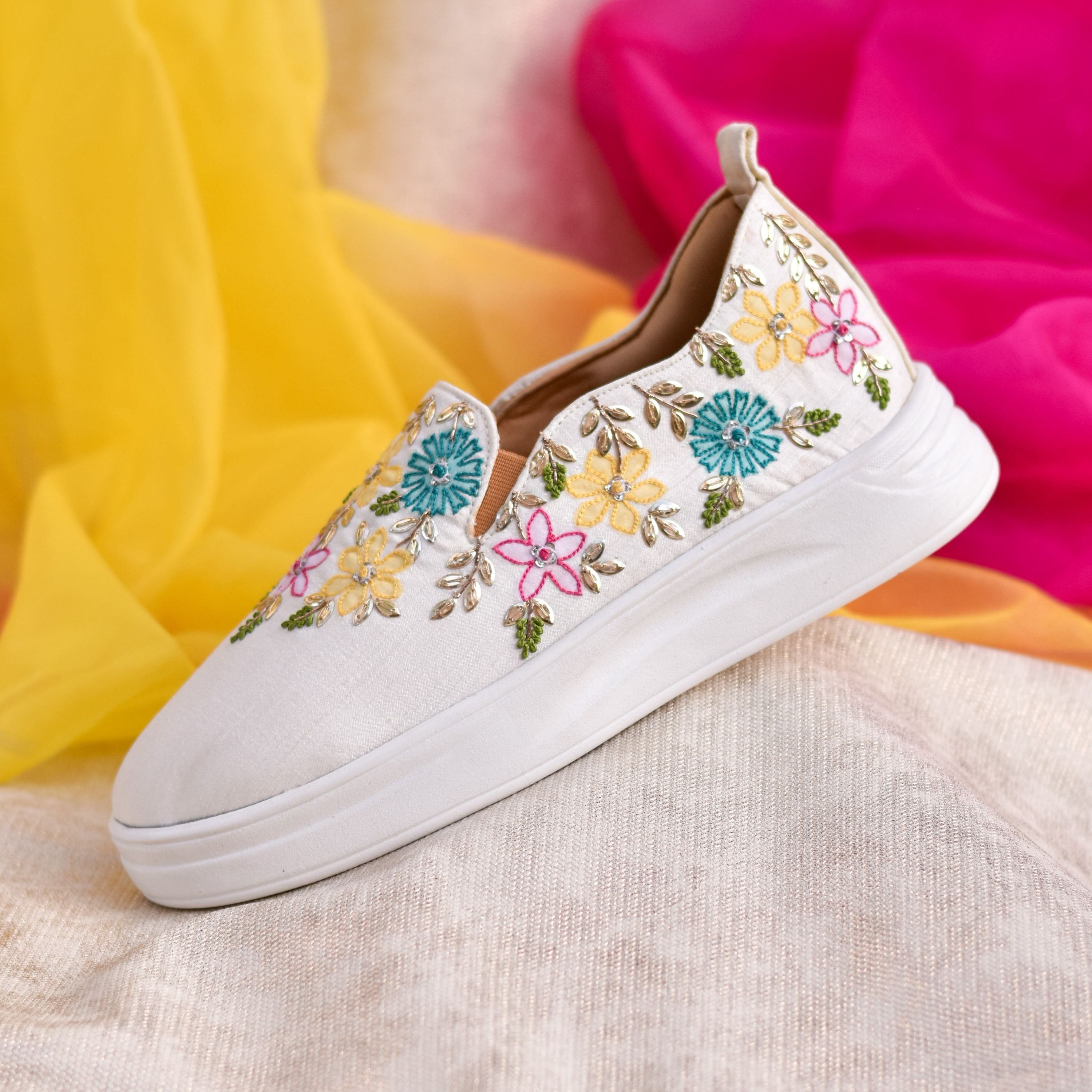 Designer festive sneakers with teal, yellow, and pink flowers.