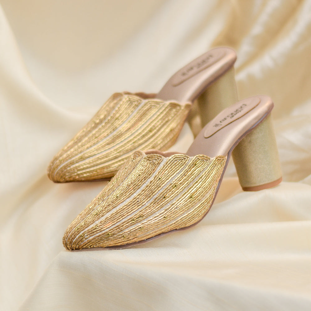 Women's gold occasion mules featuring textured handwork.
