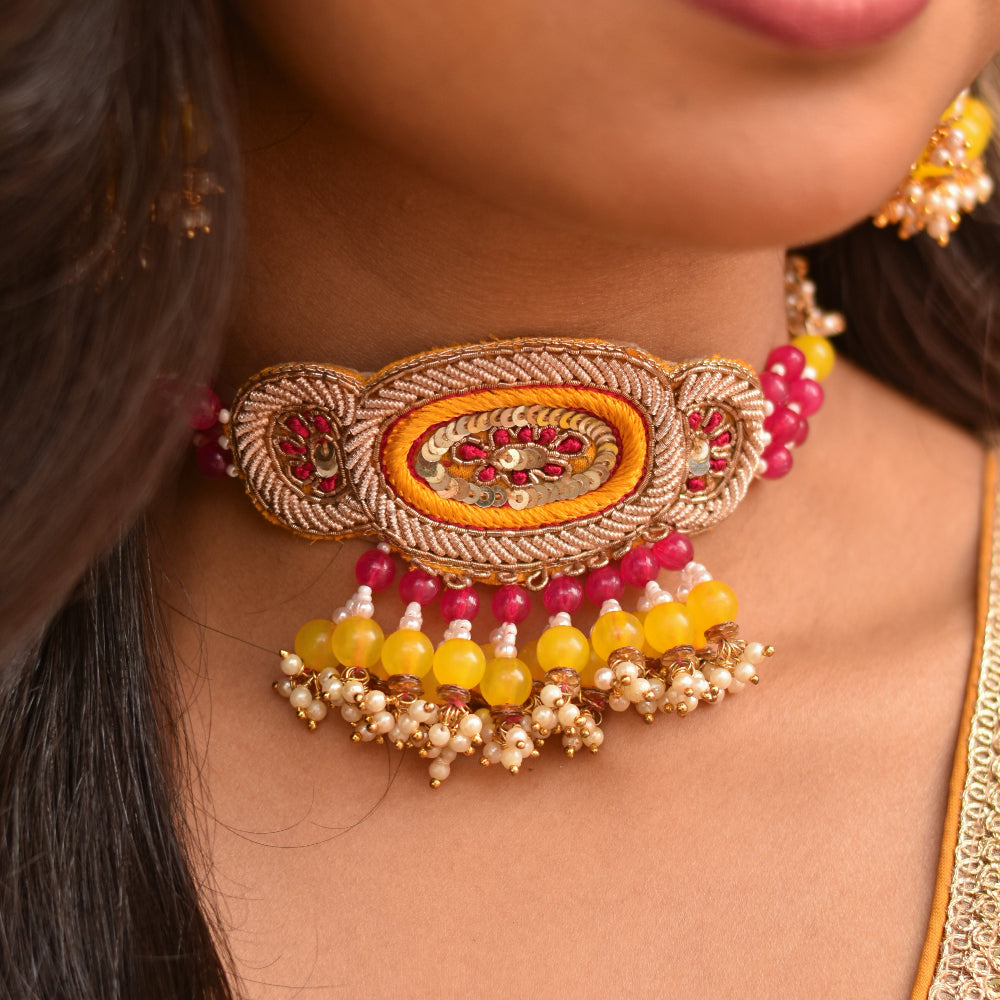 An ornate necklace with pink and yellow beads styled for haldi and prewedding functions