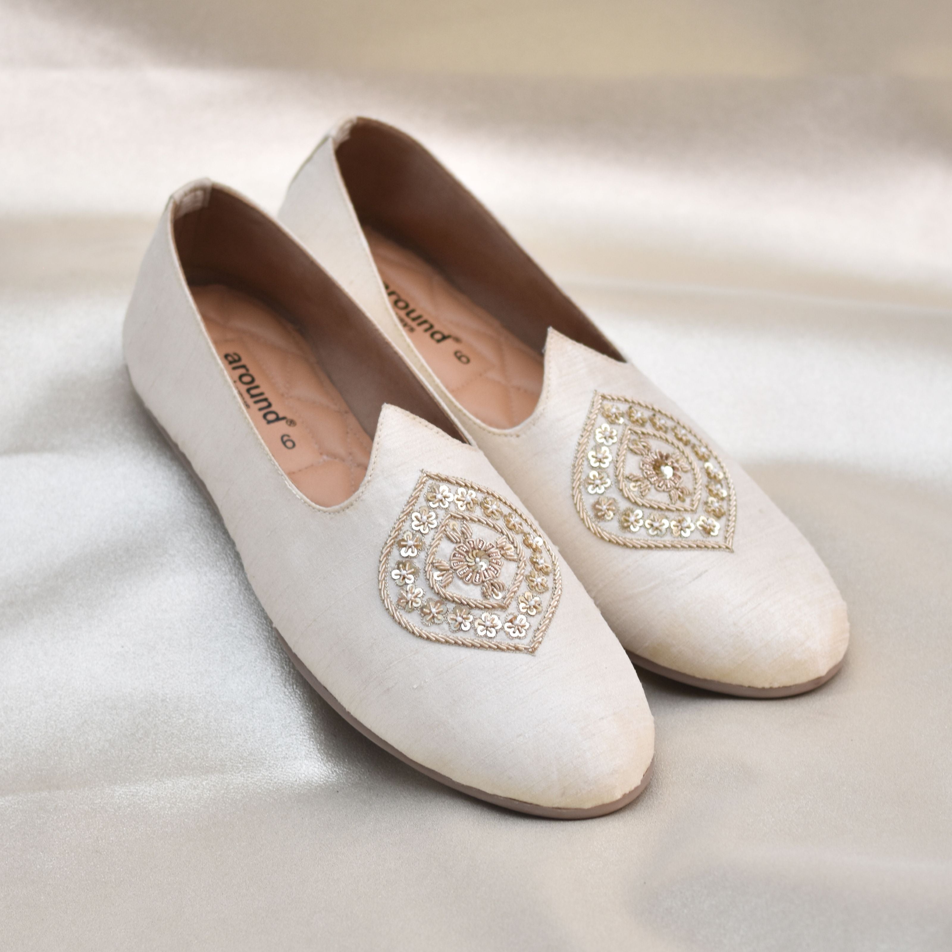 Cream men's wedding mojri with golden threadwork crest on silk finish.