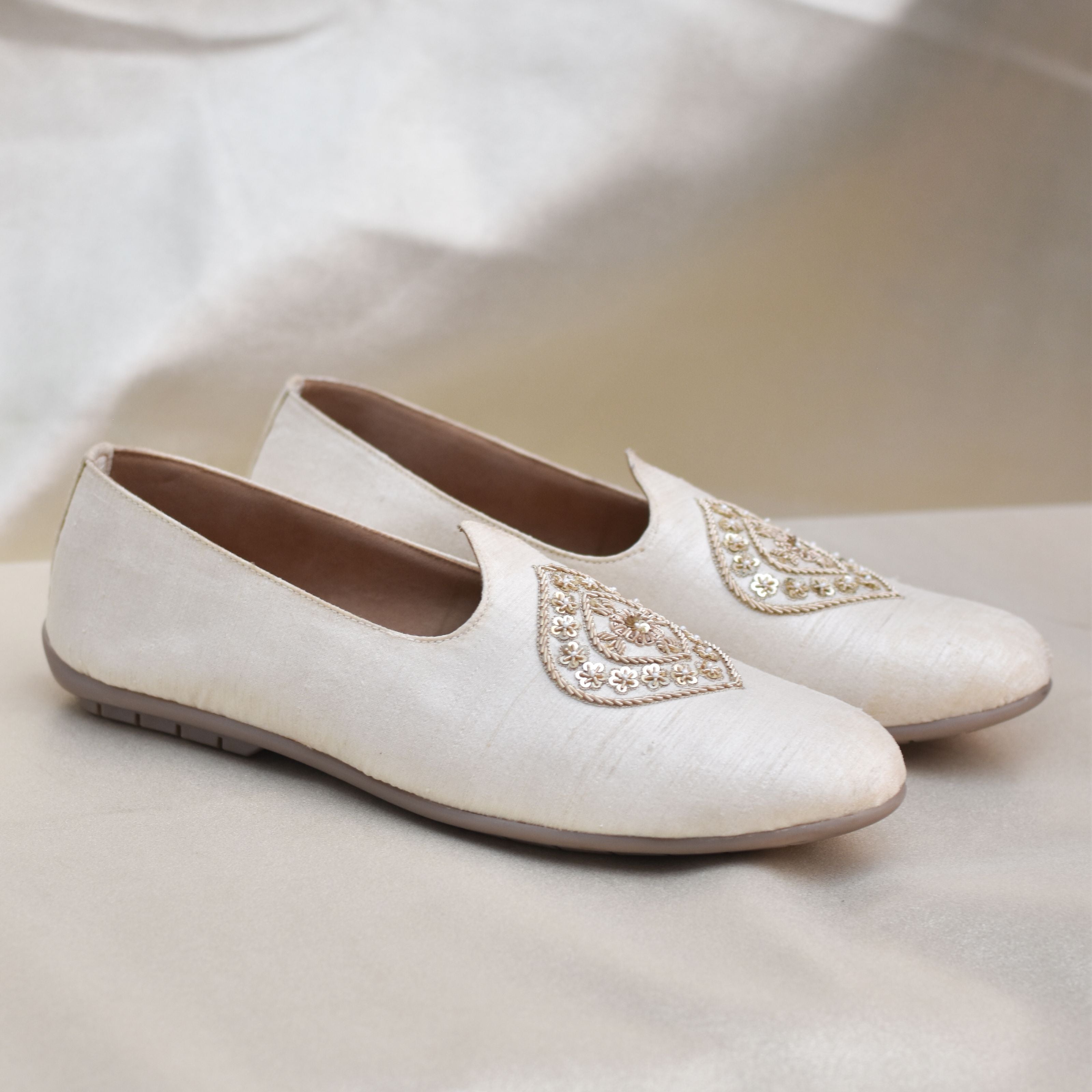 Traditional ivory groom mojri featuring ornate floral motif.