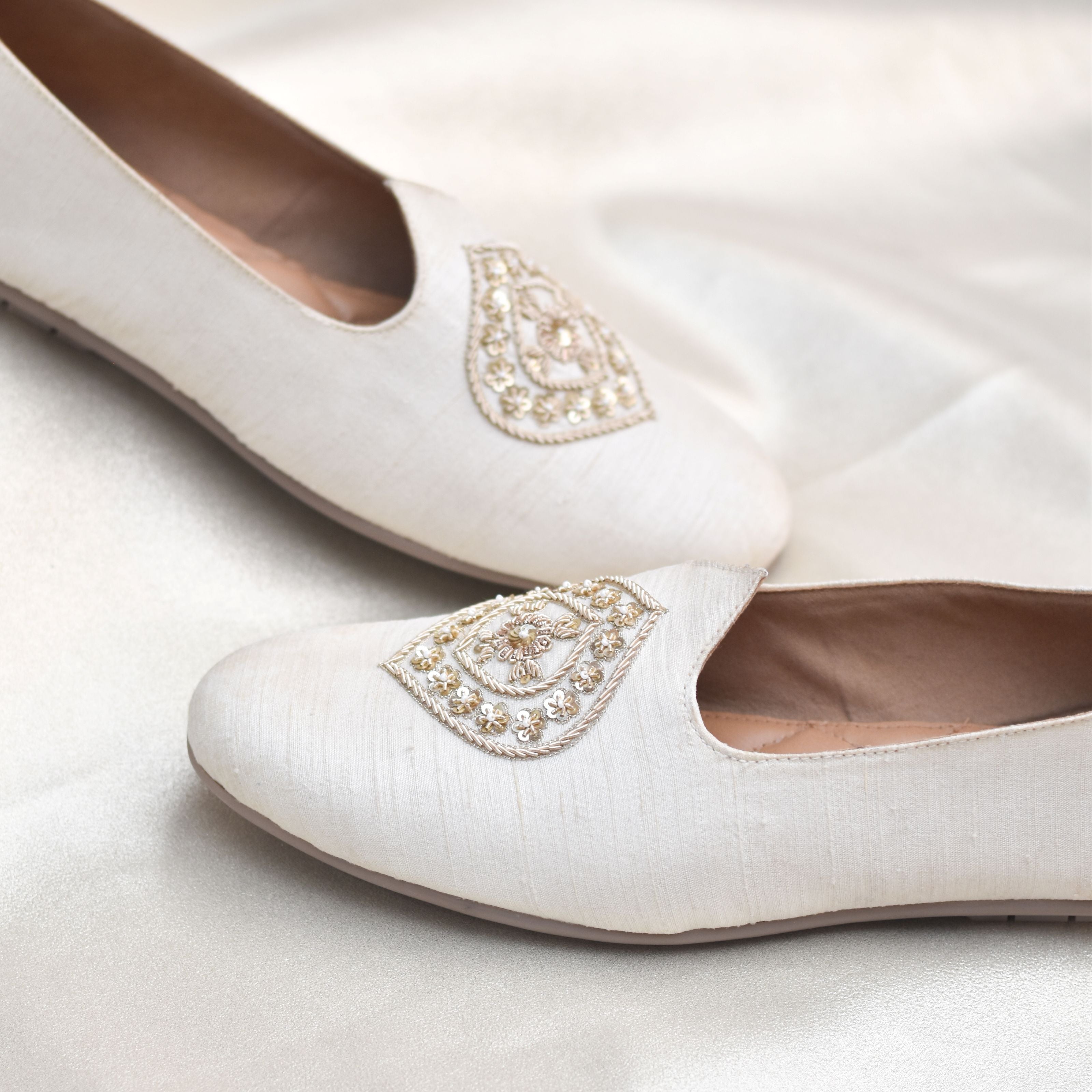 Off-white ethnic men's shoes with heritage-inspired design on textured fabric.