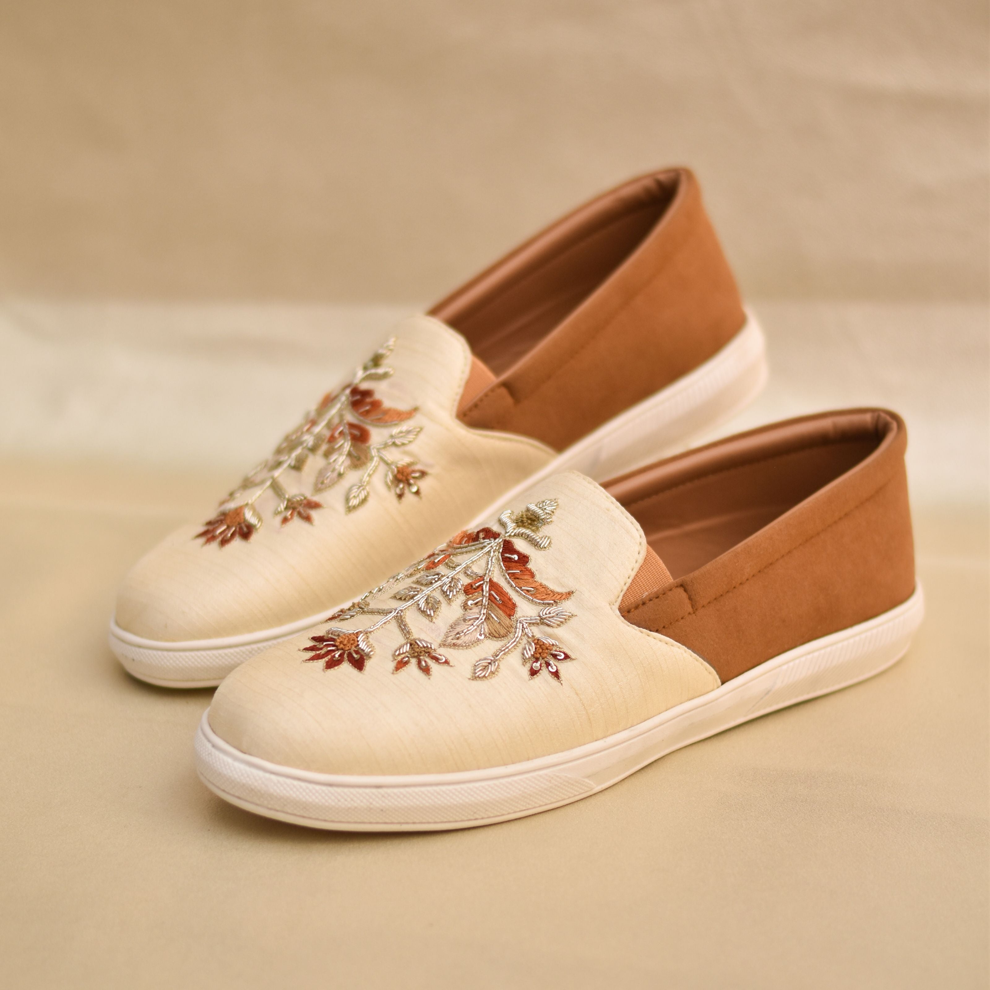 Cream men's slip-on wedding sneakers with rust and gold leaf motif detailing.