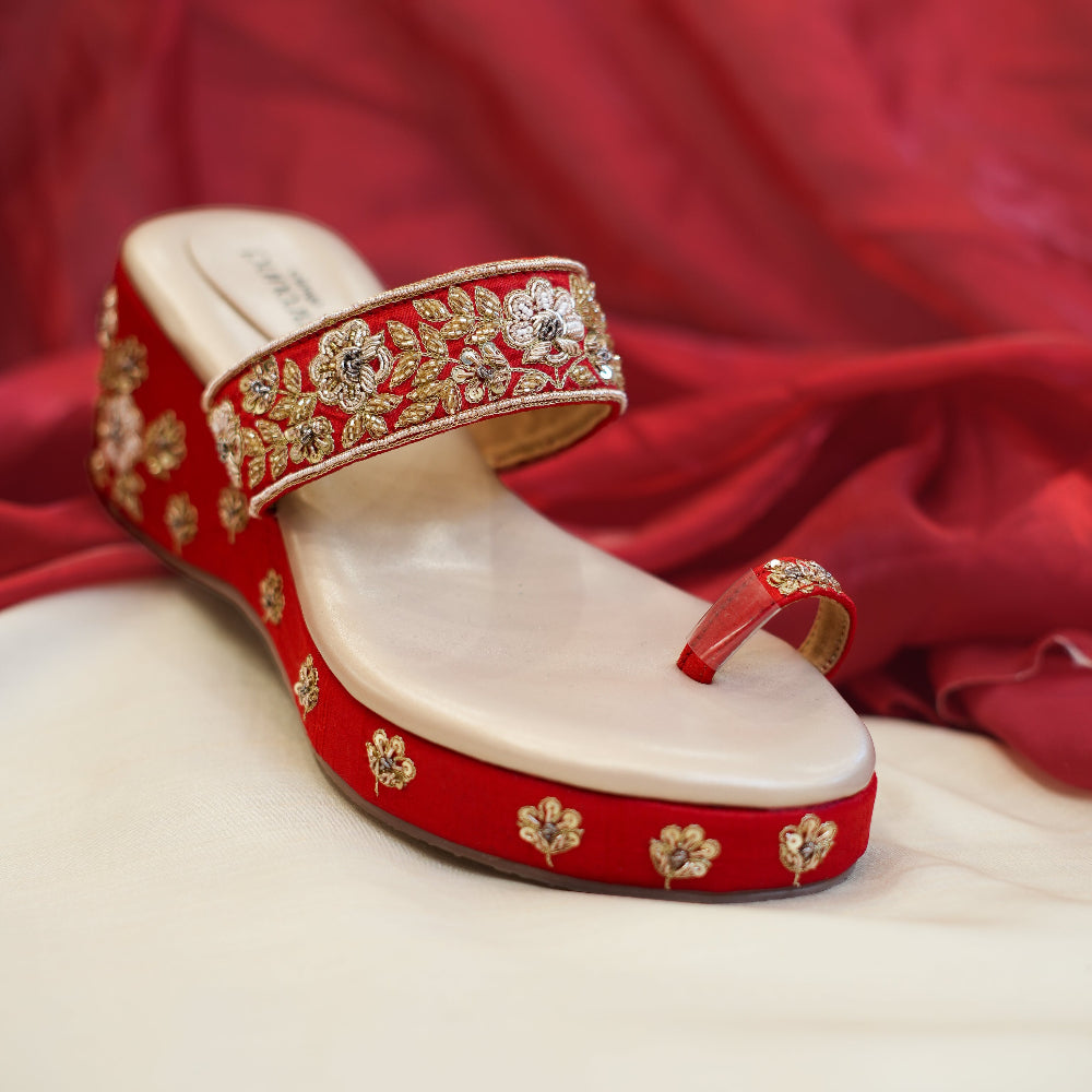 Red wedge sandals with intricate gold floral embroidery
