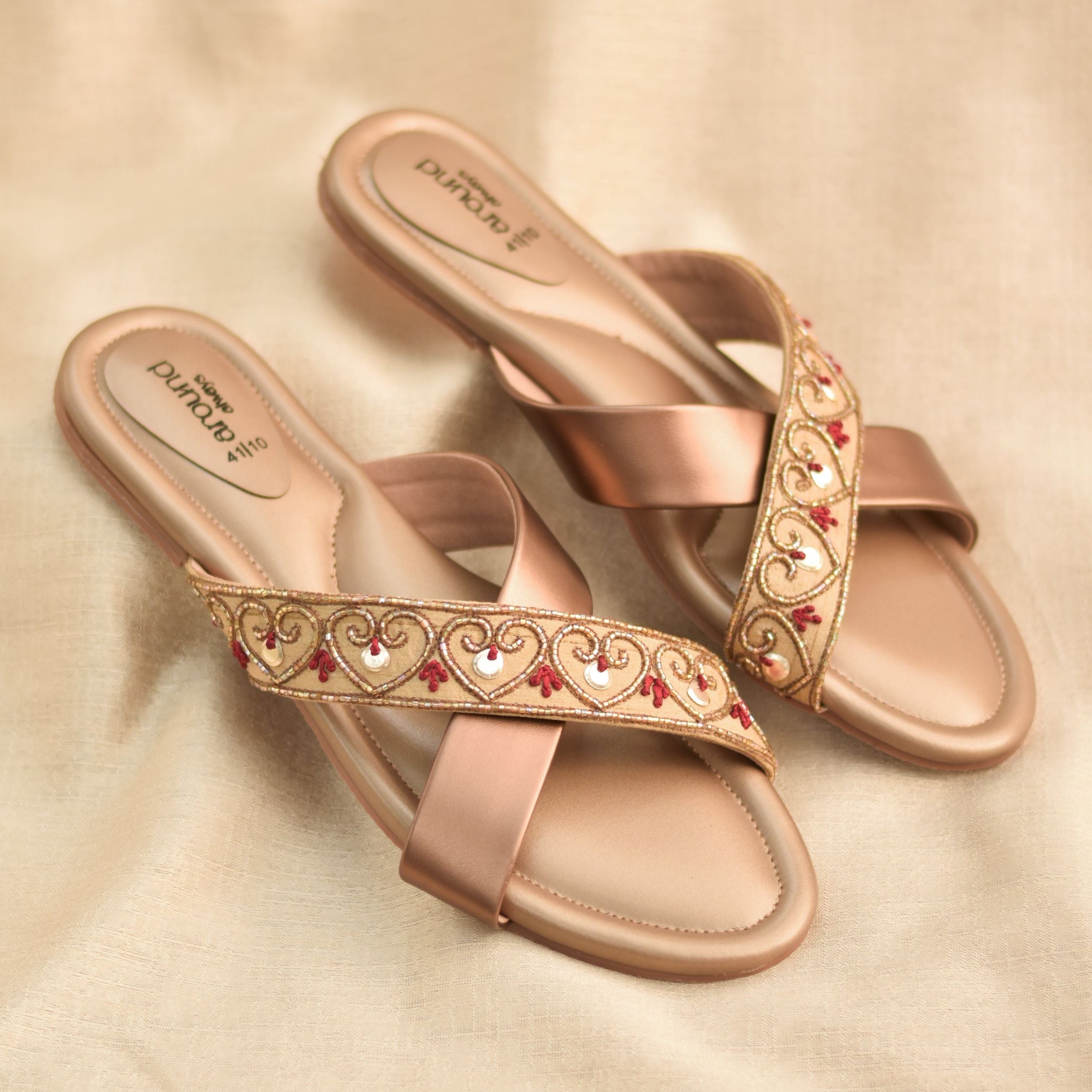 Nude crossover festive flats with golden and red embroidered strap.