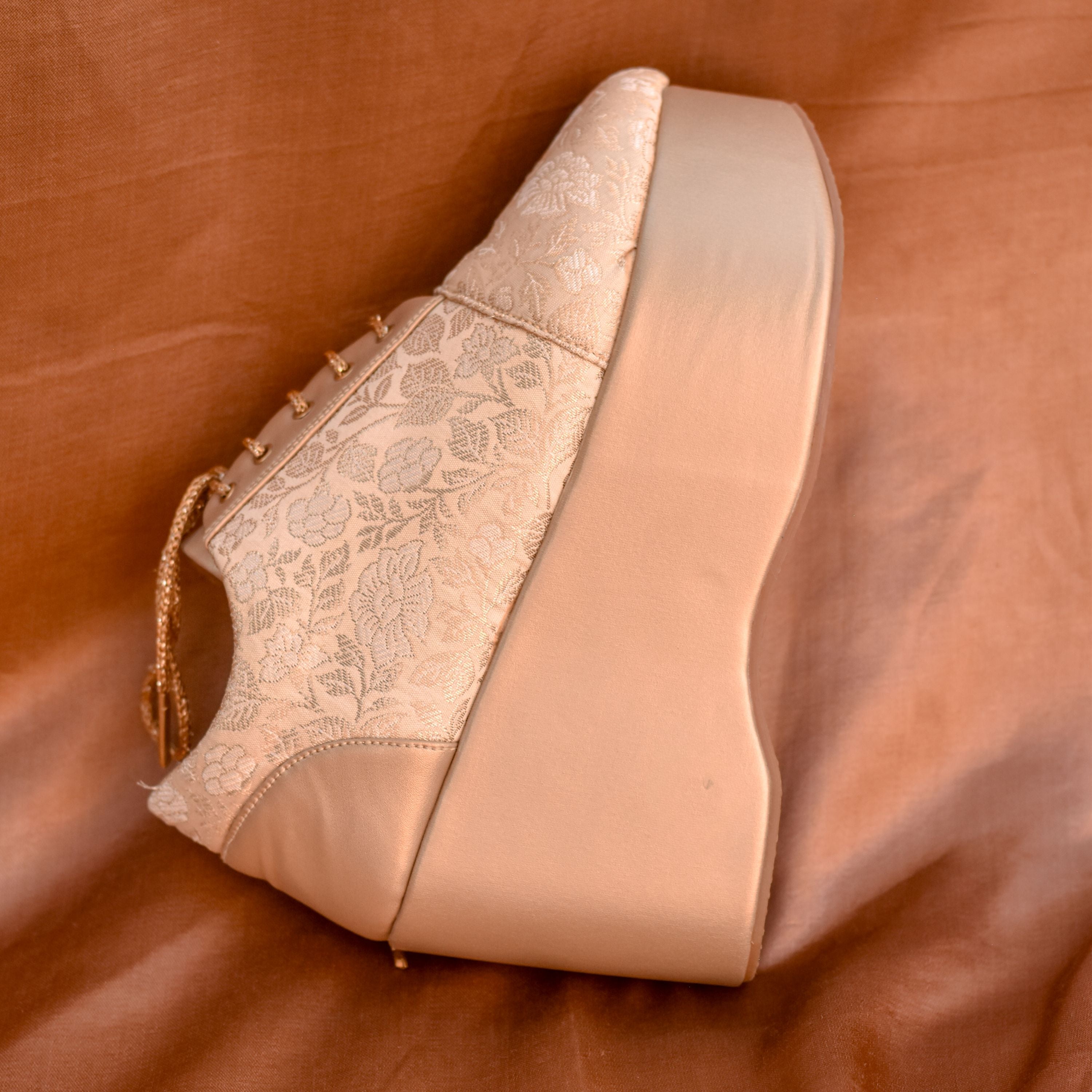 Gold wedding sneaker featuring floral woven design and platform base.