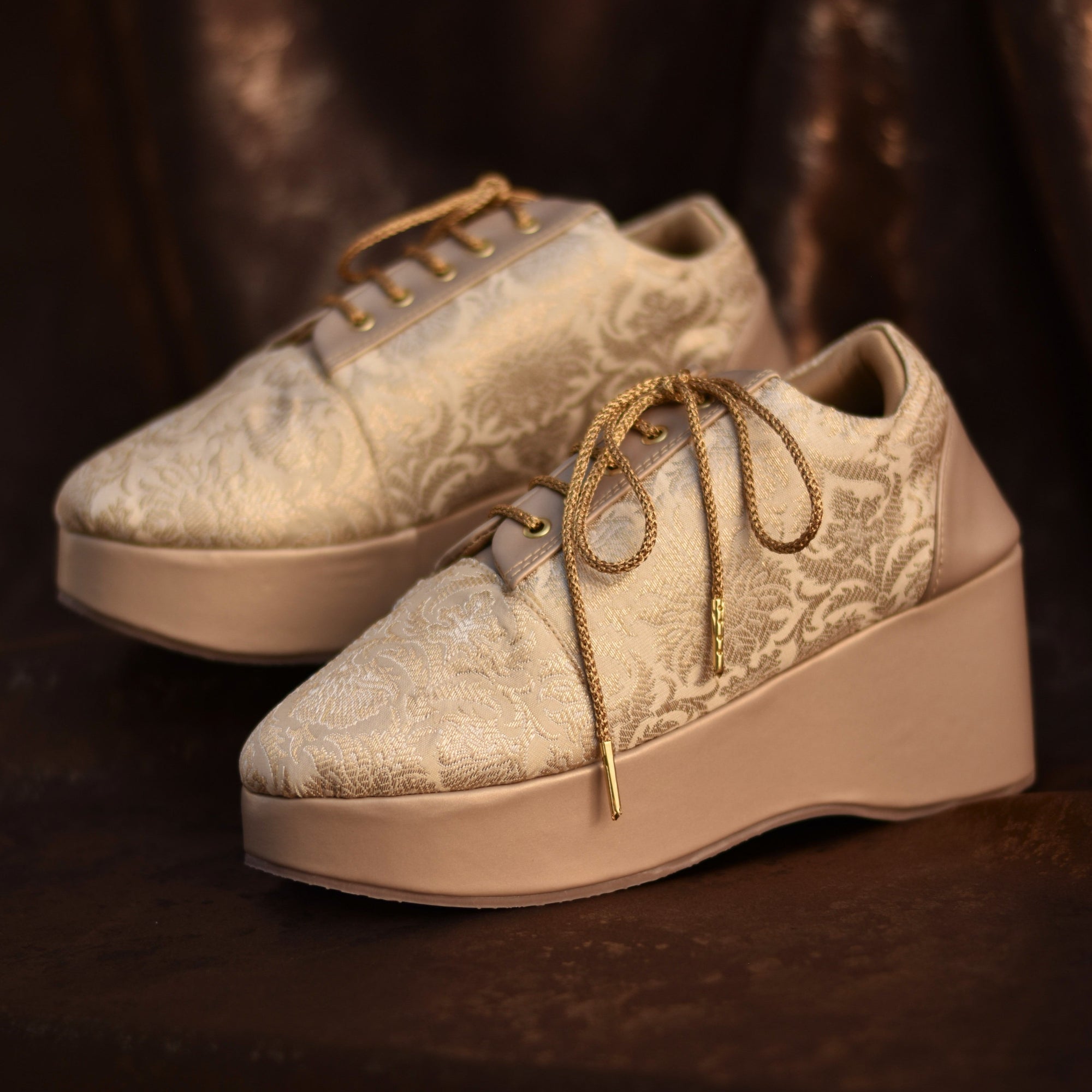 Gold fabric wedding sneaker featuring floral woven design and platform heels base.