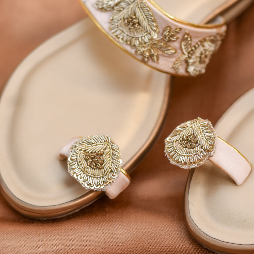 Close-up of festive ivory flats with decorative floral pattern and toe ring