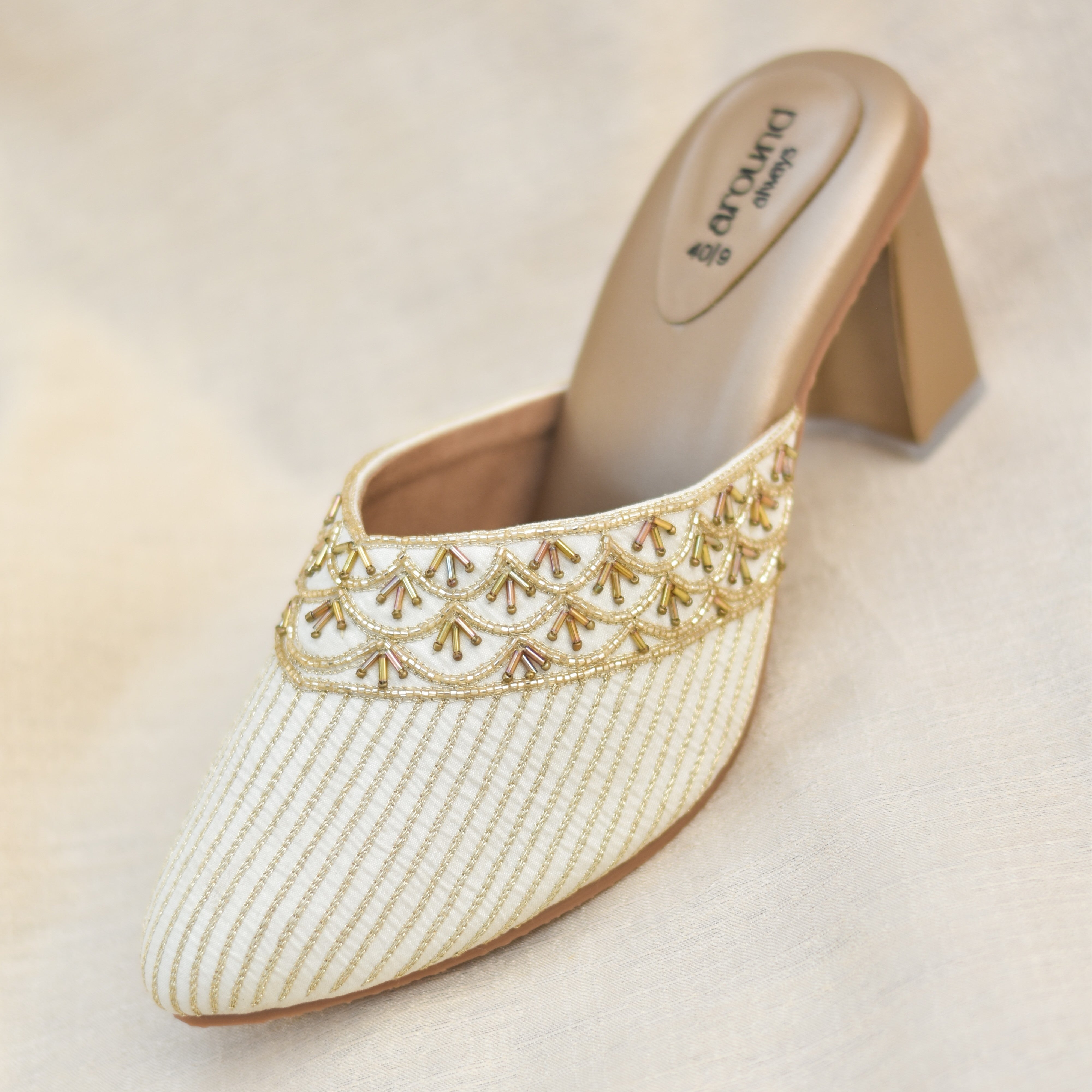 Slip-on ivory heels with metallic bead border and striped base.