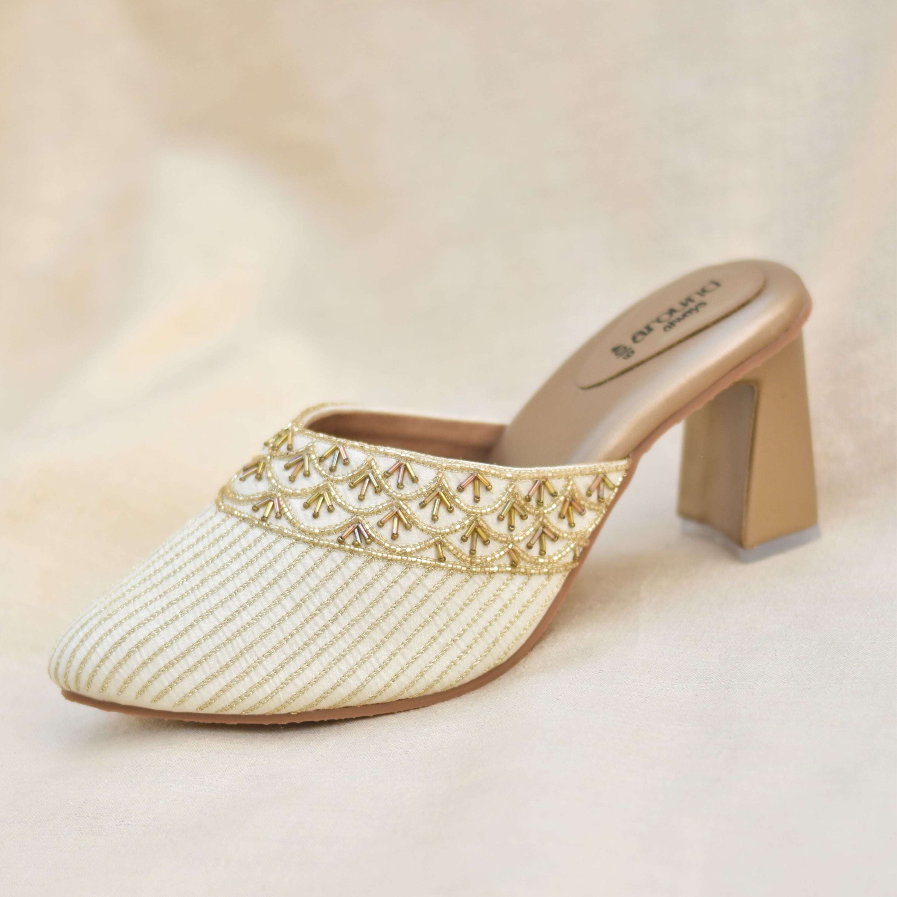 Festive ivory mules with block heels and gold threadwork.