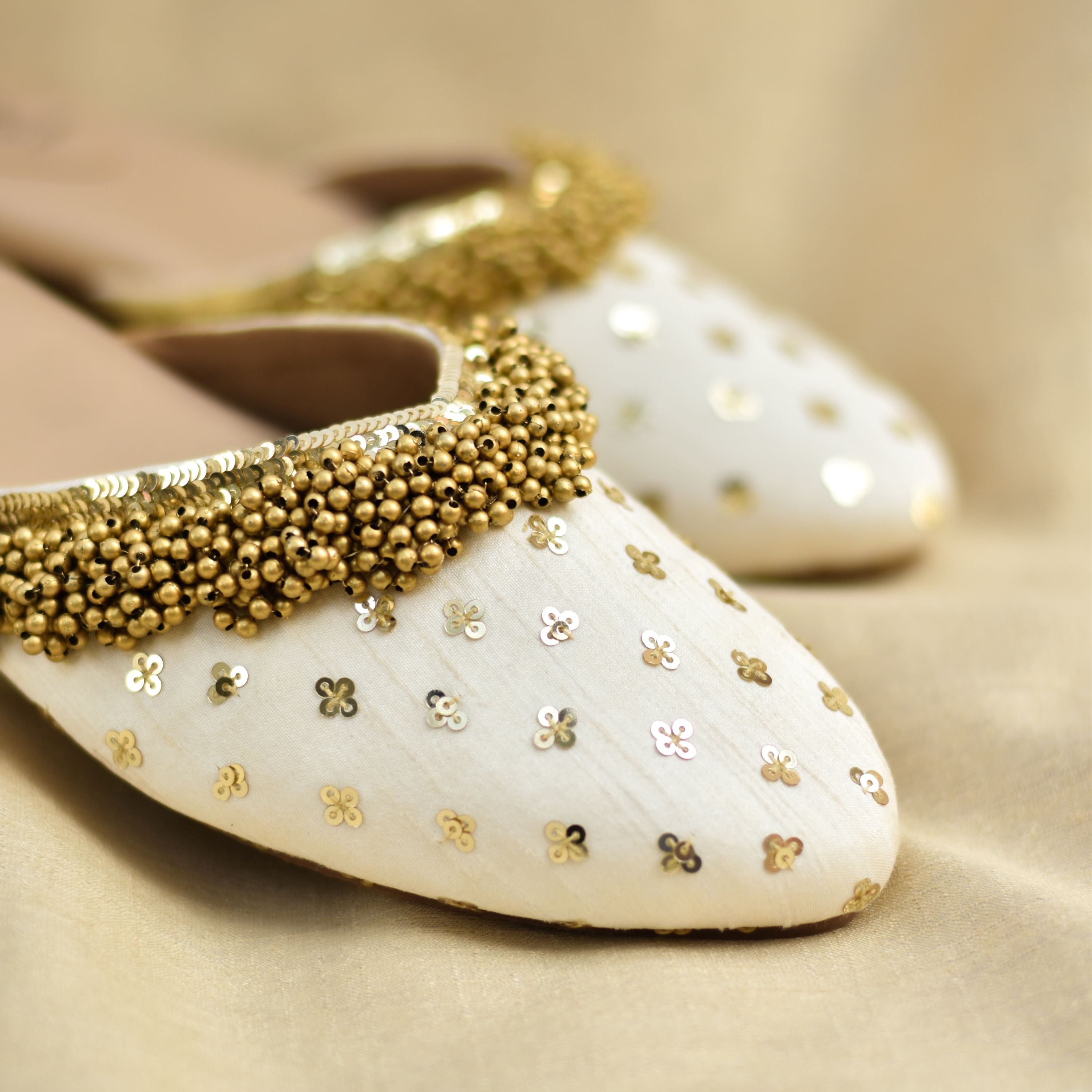 Festive ivory mules featuring metallic ghungroo detailing and gold strap.