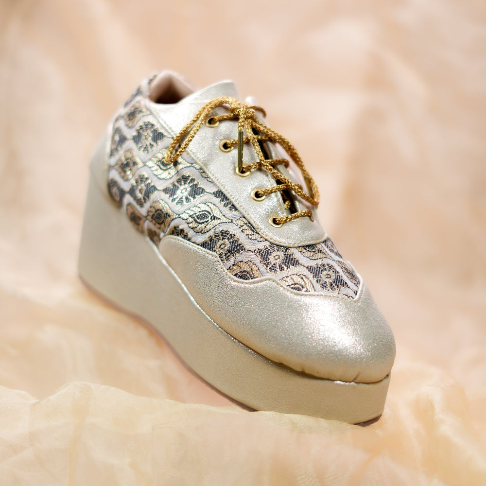 Gold sneaker wedges featuring textured brocade work and lace-up styling