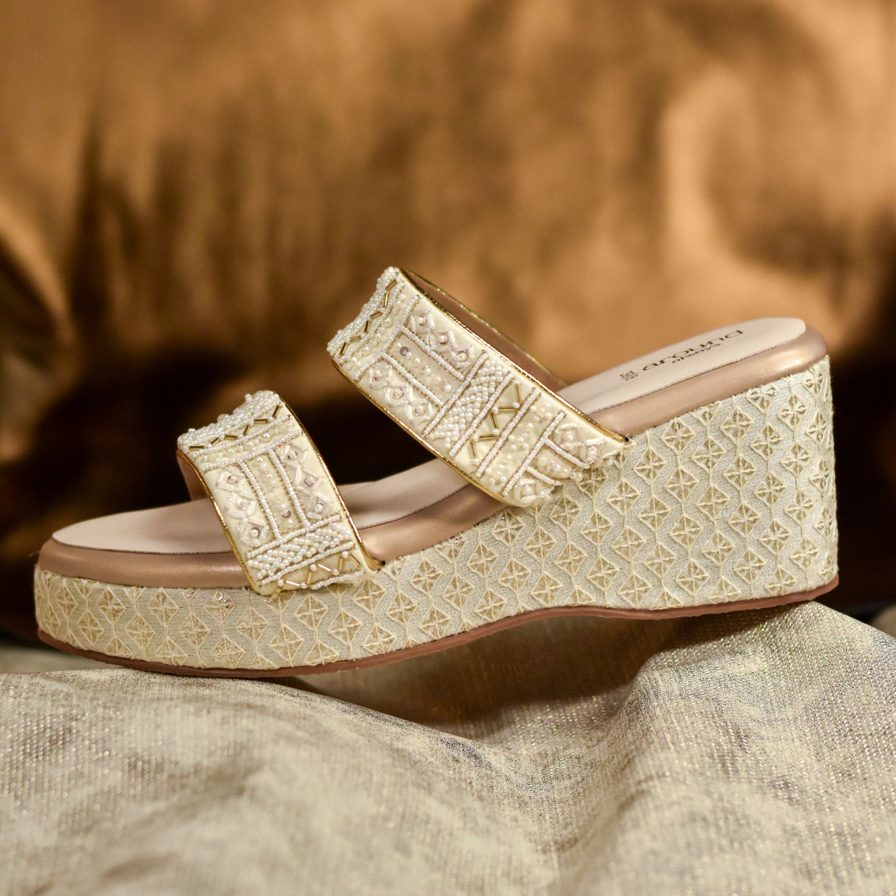 Golden wedge sandals with beaded straps and textured base.