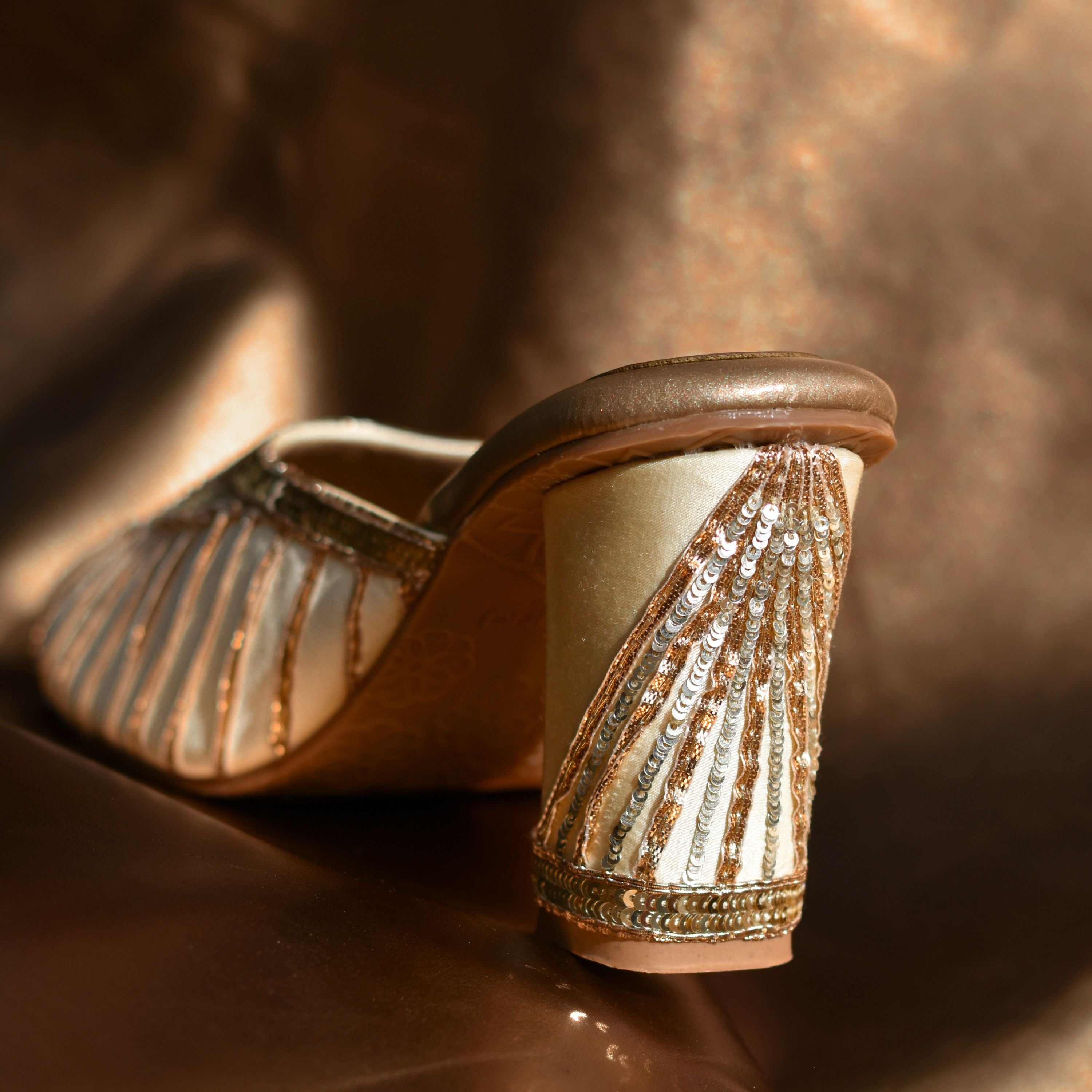 Champagne gold slip-on heels with shimmer threadwork.