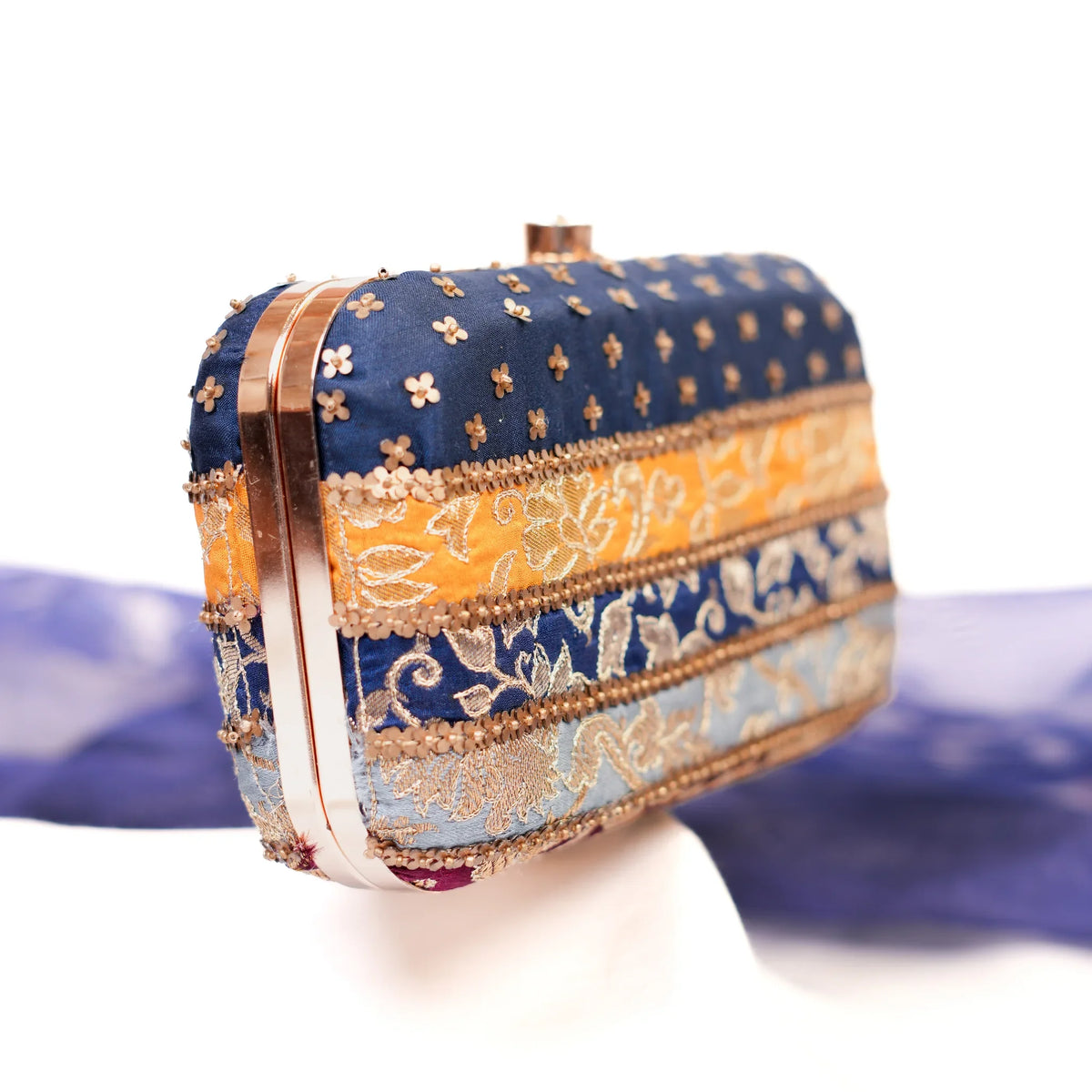 Brocade patchwork clutch with rose gold frame and gold lace bands, angled view