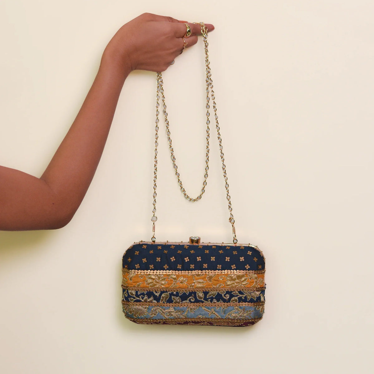 Assi clutch carried on its gold chain strap