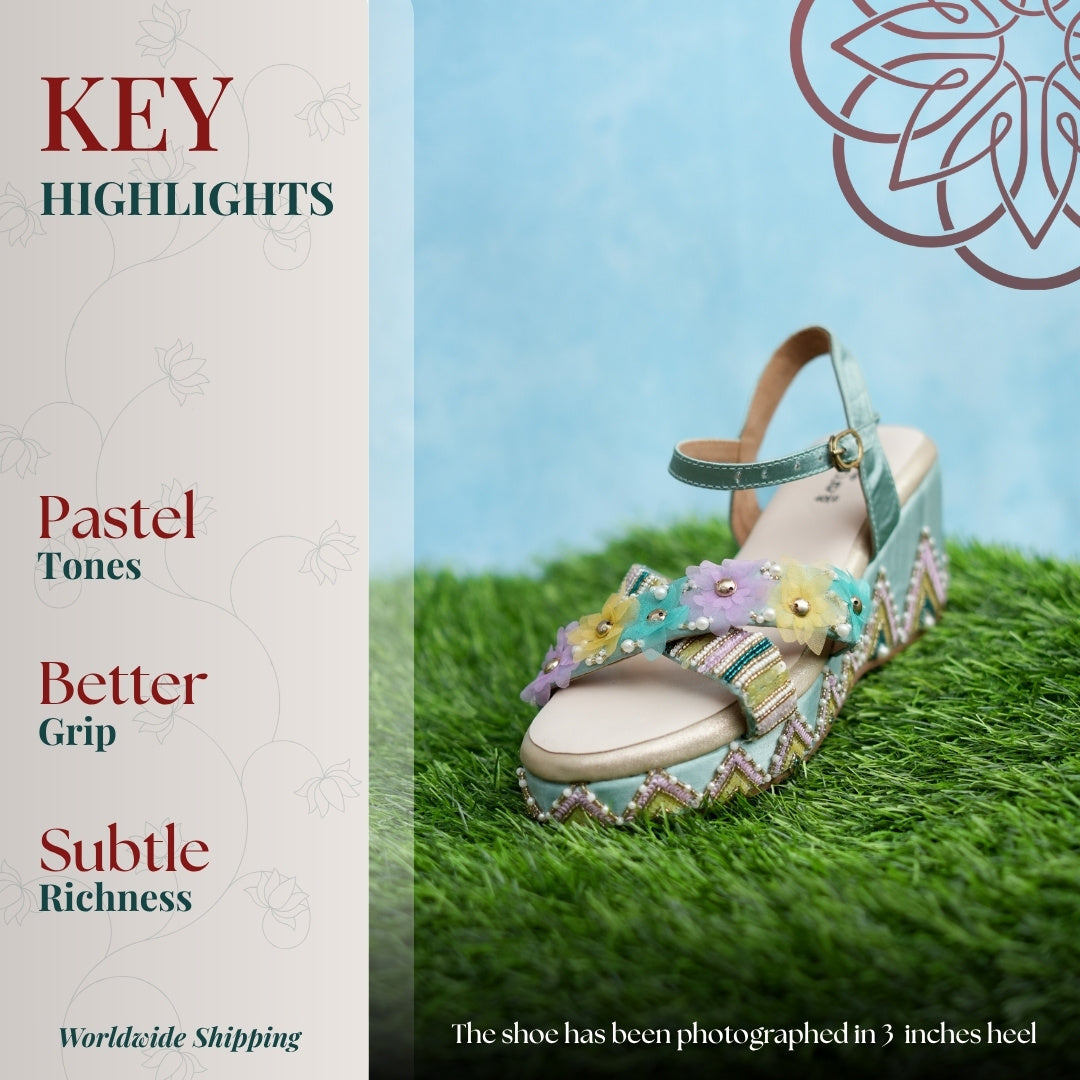 Turquoise blue wedge sandal with floral strap, multicolour detailing, patterned heel, and ankle buckle.