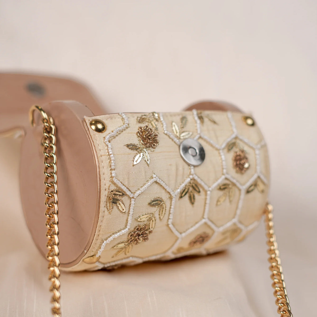 Close-up of zardozi roses inside white thread hexagons on the cream clutch