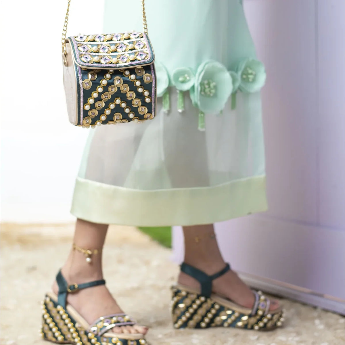 Indie bag held by its chain against a mint skirt