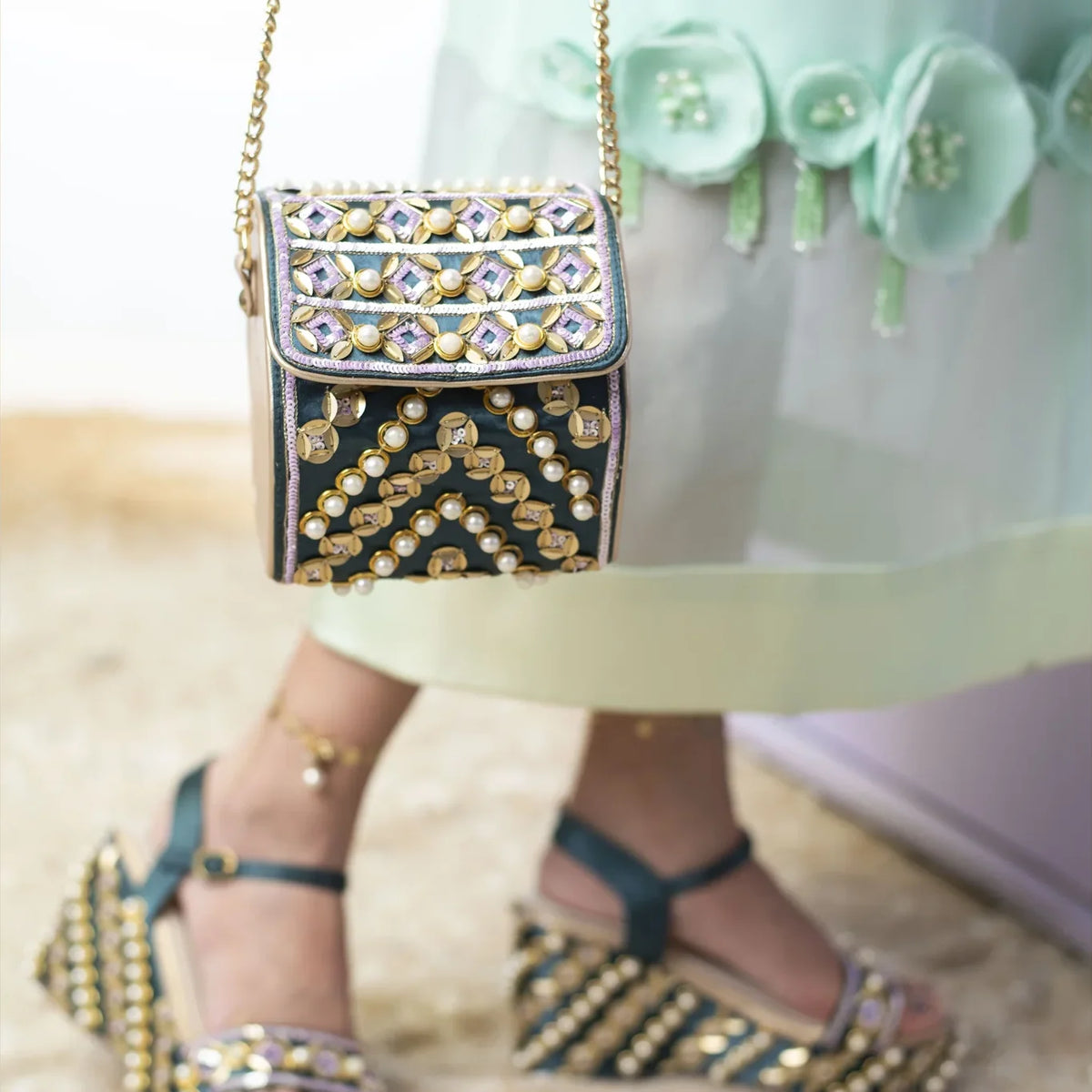 Bottle green pearl hexa bag hanging from a gold chain