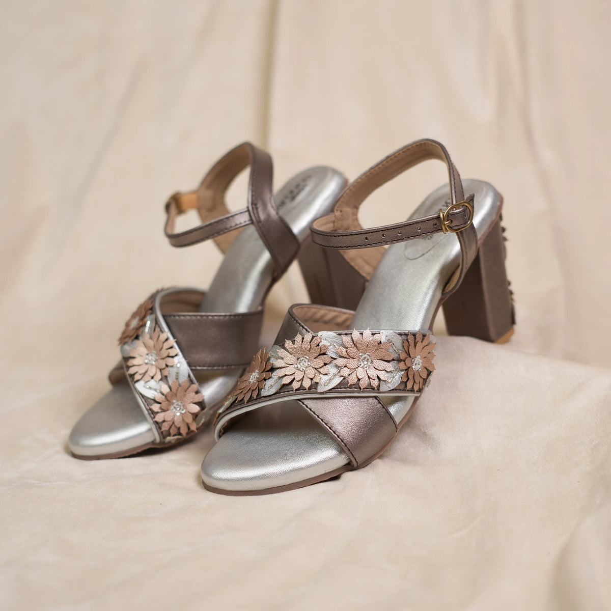 Pair of metallic cross strap party sandals with floral straps, front view