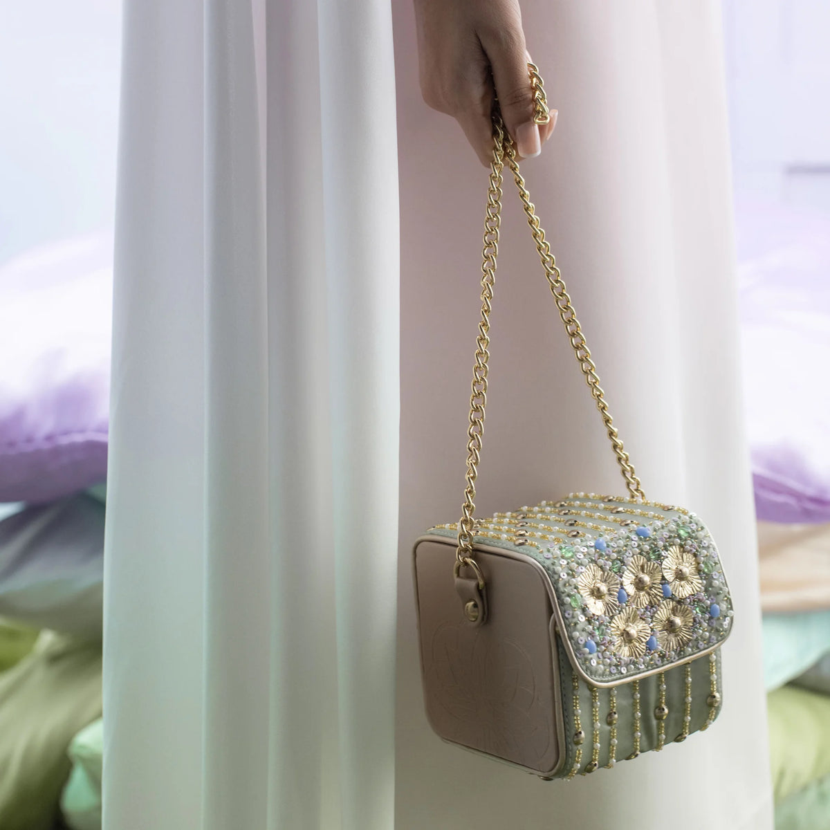 Pixie mint bag carried on a gold chain with an ivory outfit