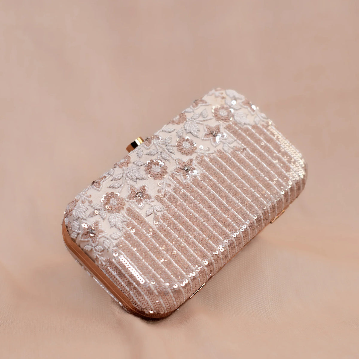 Ivory embellished box clutch for weddings with rose gold frame and crystal clasp, angled view
