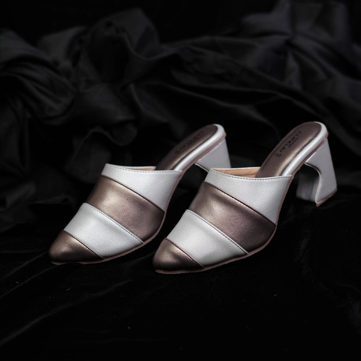 Pair of ivory and metallic striped mules for women on black background